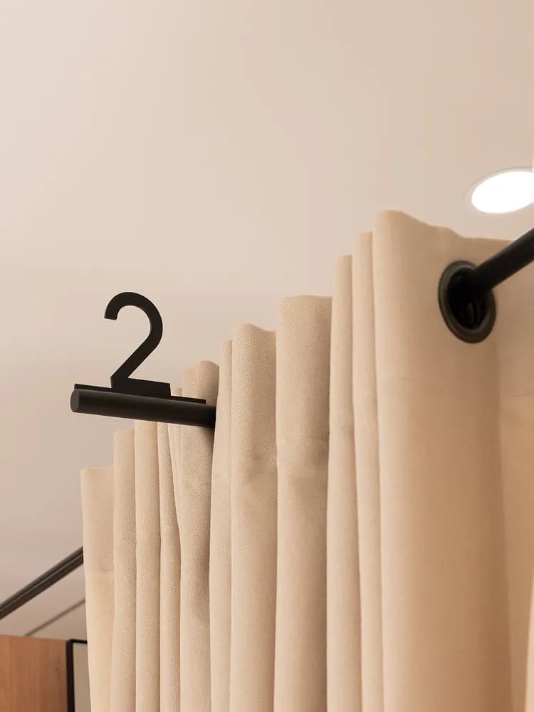 Gordijnrails van een pashokje met beige gordijn en nummeraanduiding.